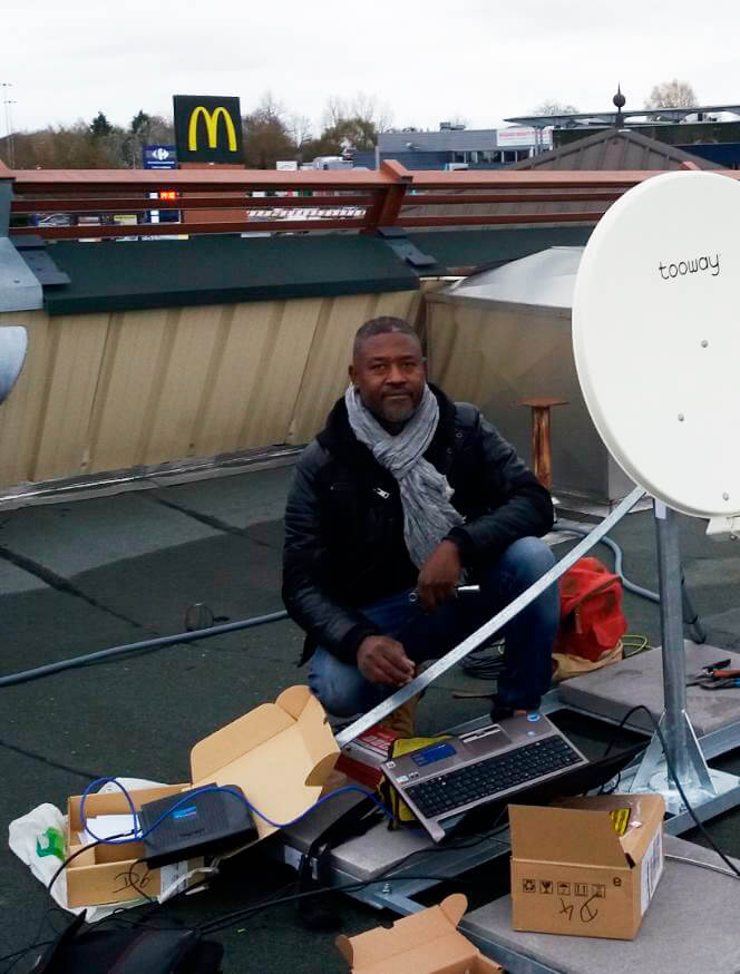 Nixon, le dirigeant de Cleansat, sur le toit d'une bâtisse en train d'installer une antenne